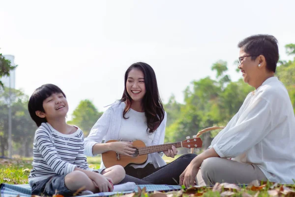 Mutlu Asyalı aile hafta sonları ya da tatillerde parkta boş vakit geçirir. Sağlıklı bir büyükanne ve sevgili bir oğul, kızının veya annesinin gitar çalmasından hoşlanırlar. Aile üretimi ilişkisi ya da fotoğraf konsepti