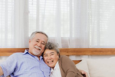 Asyalı, mutlu, emekli, yaşlı, gülümseyen, sevimli bir çift evde el ele tutuşuyorlar. Emeklilikten sonra mutlu bir yaşam tarzı olan güzel bir evlilik aşığının romantik ilişkisi
