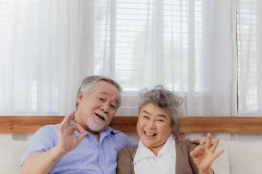 Asyalı, mutlu, emekli, yaşlı, gülümseyen ve evde birlikte gülen sevimli bir çift. Emeklilikten sonra mutlu bir yaşam tarzı olan güzel bir evlilik aşığının romantik ilişkisi.