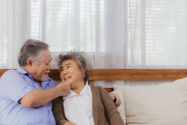 Asyalı, mutlu, emekli, yaşlı, gülümseyen, sevimli bir çift evde dans etmekten zevk alıyor. Emeklilikten sonra mutlu bir yaşam tarzı olan güzel bir evlilik aşığının romantik ilişkisi