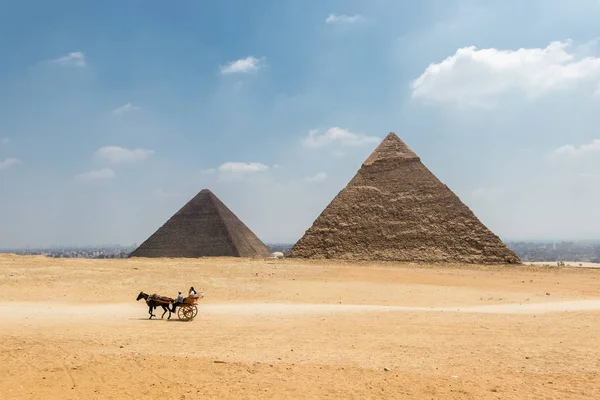 Horse carriage with tourists in front of the Pyramid of Khufu an