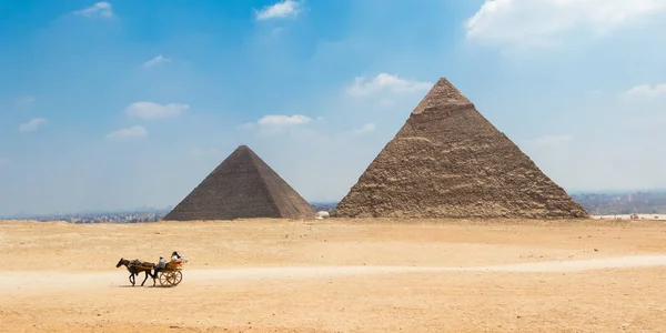 Horse carriage with tourists in front of the Great Pyramids of Giza, Egypt