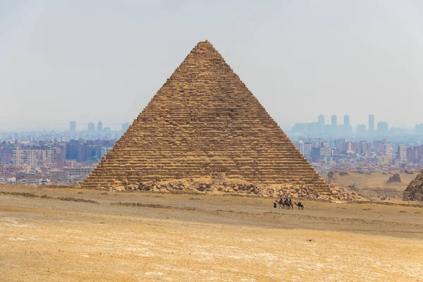 Kamel husvagn med turister framför de stora pyramiderna i Giza, Egypten — Stockfoto