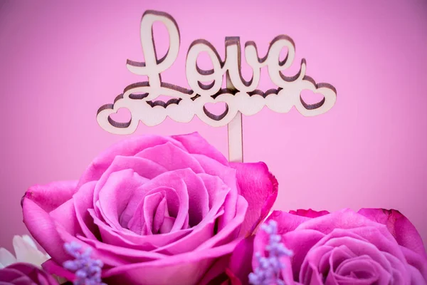 Miłość, kreatywne różowe kwiaty róż na różowym tle i Word Love. Pojęcie miłości — Zdjęcie stockowe