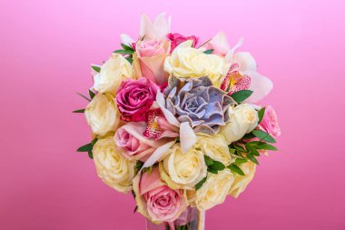 Gelinlerin çiçek buketindeki güller pembe duvarın arkasında.