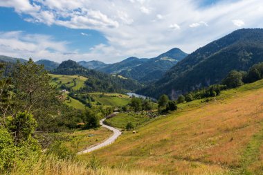 Sırbistan 'daki Tara milli parkındaki dağlar, çayırlar, tepeler ve küçük köy evleri ve barajın dramatik manzarası