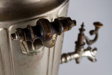 Gri arka planda ahşap sapları olan antika bir semaver.