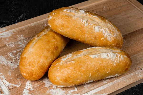 Kesme tahtasındaki taze beyaz ekmek ve siyah ahşap bir masa.
