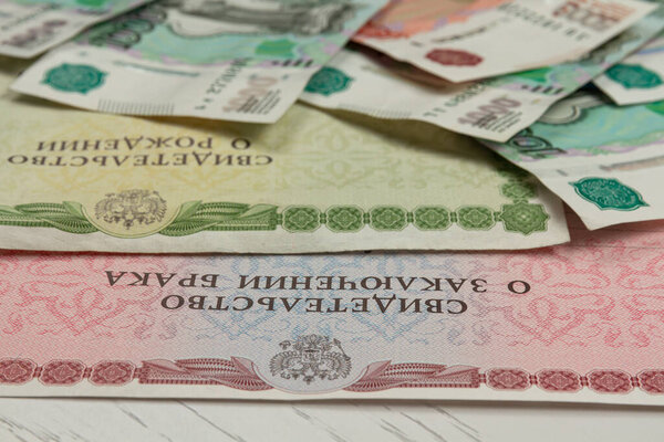 documents and paper money are on the table inscription birth and marriage certificate