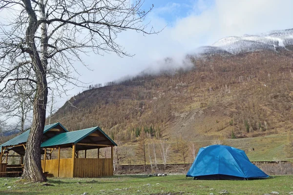 Tourist tent and wooden gazebo are at the foot of the mountains at the tourist base