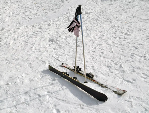 Дитячі альпійські лижі, лижні стовпи та рукавички лежать на снігу — стокове фото