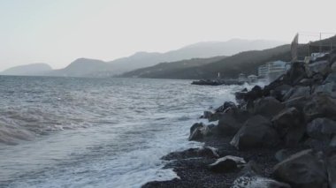 Dalgalar yavaş çekimde kayalara çarpıyor.