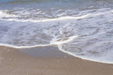 Deniz suyu dalgalarıyla yıkanan ıslak deniz kumu.