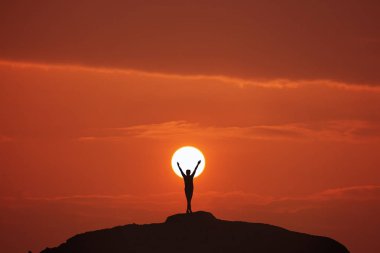 Gün batımının arka planında sırt çantalı bir adamın silueti.