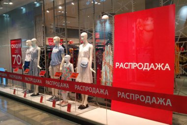 Sale in a clothing store with mannequins in the shop window. Text in Russian: discounts up to 70%