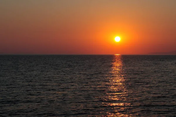 Setting sun over the sea, clear (reddish) sky