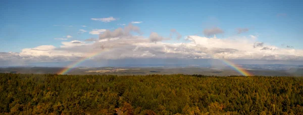 Rainbow over the forest - autumn landscape with rainbow, blue sky and white clouds, view from view tower Decinsky sneznik (Hoher Schneeberg), Czech republic