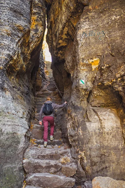 woman climbs the stairs through a rift in the rocks