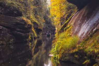 The Kamnitz Gorge - a boat with a ferryman and tourists on the river flowing through rocky ravine in Bohemian Switzerland, Czech Republic clipart