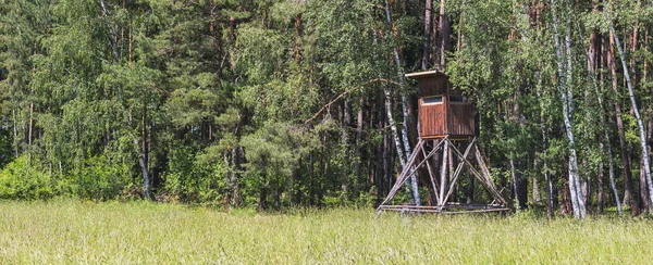 wooden hunting blind on the edge of the forest, near the meadow