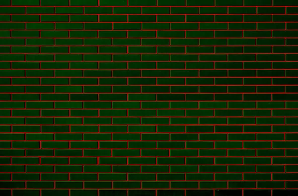 Brick wall of green bricks with a red seam