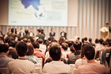 Sahnede, iş ve eğitim yatırım kavramı hakkında hoparlörlere sahip konferans salonu veya seminer toplantı seyirci görünümünde arka