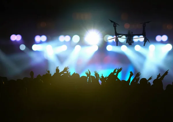ステージの前面にフォロー アップ Songer ショー手のアクションと音楽ファンクラブのシルエットでコンサートの群集のビデオを撮影のための飛行ドローンのクローズ アップ シルエットに従う光 — ストック写真
