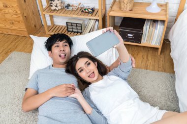 Mutlu Asya halı yatak, Çift selfie kavramı ile katta selfie için teknoloji akıllı telefon kullanarak aşık üstten görünüm,