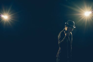 Asya spot ışığı ve Mercek Parlaması, müzikal konsepti ile siyah arka plan üzerinde mikrofon ile bir şarkı söylerken müzisyen