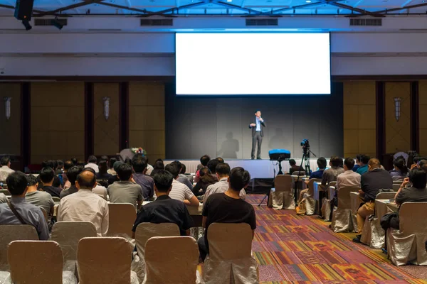 Arka tarafında oturan ve düşük ışık konferans salonu, olay ve seminer kavramı sahnede speackers dinleme kitlelere