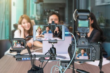 Profesyonel kamera ve akıllı cep telefonu ile fotoğraf makinesi tripod üzerinde canlı akışı, Live Streaming için girişimci konsepti ile röportaj veren grup Asya iş adamları set üzerinde