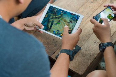 Chiangmai, Tayland - 25 Mart 2018: Arkadan görünüm tanımlanmamış erkeklerin ipad ve iphone Garena Rov cep oyun online kahve dükkanında 25 Mart, 2018 chiang mai Eyaleti, Tayland oynarken kullanarak