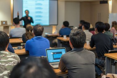 Arka tarafında oturan ve toplantı odası, olay ve seminer kavramı düşük ışıkta sahnede speackers dinleme kitlelere