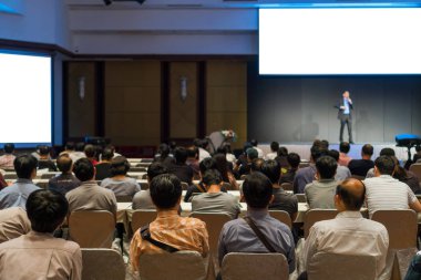 Arka tarafında oturan ve düşük ışık konferans salonu, olay ve seminer kavramı sahnede speackers dinleme kitlelere