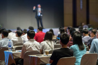 Arka tarafında oturan ve düşük ışık konferans salonu, olay ve seminer kavramı sahnede speackers dinleme kitlelere