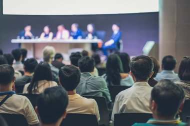Seyirci arkadan görünüş hoparlörlere sahip konferans salonu veya seminer toplantıyla beyin fırtınası ve sahne, iş ve eğitim yatırım kavramı hakkında konuşmak vardır