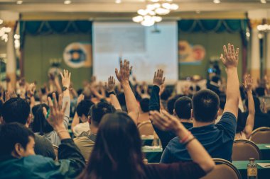 Konferans salonu veya Seminer Toplantı, iş ve eğitim kavramı sahne alanı'ndaki hoparlörden soruyu cevaplamak için el gösterilen seyirci arkadan görünüş