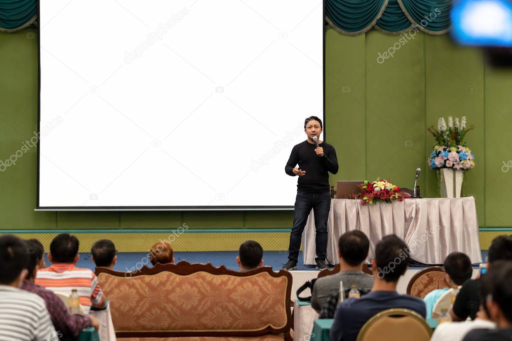 Closeup portrait of asian Speaker with casual suit on the stage over the presentation screen in the conference hall or seminar meeting, business and education concept