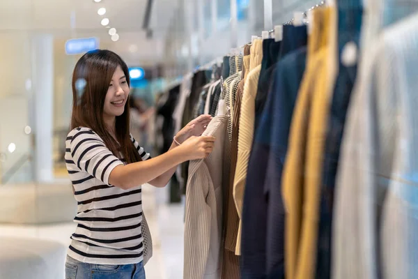 快乐的亚洲妇女选择衣服在商店与快乐行动在部门中心 — 图库照片