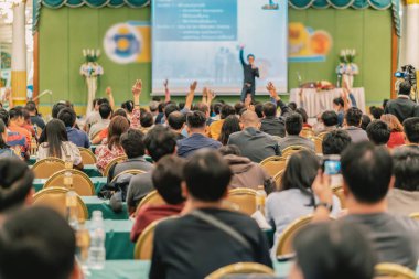 Konferans salonu veya Seminer Toplantı, iş ve eğitim kavramı sahne alanı'ndaki hoparlörden soruyu cevaplamak için el gösterilen seyirci arkadan görünüş
