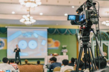 Arka yan Video fotoğraf için Asya hoparlör casual elbise ile sahne alanı'nda alarak kameraman mevcut konferans salonu veya Seminer Toplantı, olay ve seminer üretim kavramı içinde belgili tanımlık perde