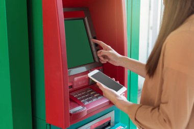 Atm önünde iş otomatik vezne makinesi kavramı geri çekilmesi için akıllı cep telefonu kullanan kadın
