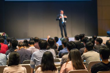 Arka tarafında oturan ve düşük ışık konferans salonu, olay ve seminer kavramı sahnede speackers dinleme kitlelere