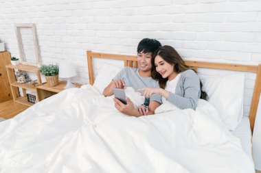 Mutlu Asya selfie evde, yatak odasında yatağın üstünde için teknoloji akıllı telefon kullanarak aşık çift selfie kavramı,