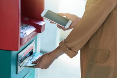 Atm önünde iş otomatik vezne makinesi kavramı geri çekilmesi için akıllı cep telefonu kullanan kadın