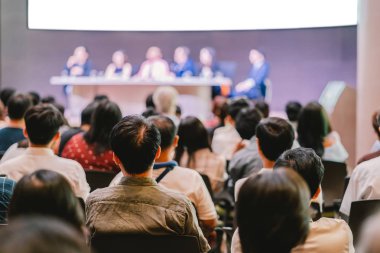 Seyirci arkadan görünüş hoparlörlere sahip konferans salonu veya seminer toplantıyla beyin fırtınası ve sahne, iş ve eğitim yatırım kavramı hakkında konuşmak vardır