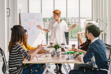 Asya İş kadını, modern işyerinde rahat bir eylem de beyin fırtınası ve birlikte çalışan, asya ve çok ırklı İş adamları Grubu önünde proje şeması ile proje sunan, insan iş grubu kavramı
