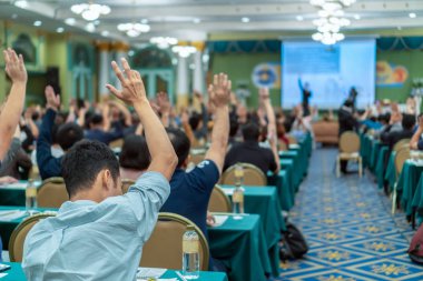 Konferans salonu veya Seminer Toplantı, iş ve eğitim kavramı sahne alanı'ndaki hoparlörden soruyu cevaplamak için el gösterilen seyirci arkadan görünüş