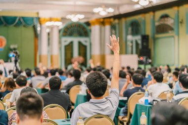 Konferans salonu veya Seminer Toplantı, iş ve eğitim kavramı sahne alanı'ndaki hoparlörden soruyu cevaplamak için el gösterilen seyirci arkadan görünüş