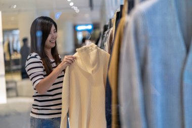 Mutlu Asyalı kadın mağaza dükkan bölümü merkezi mutlu eylemle giysiler seçmek